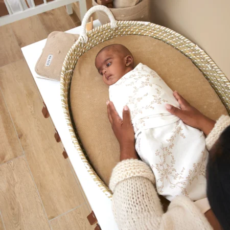 Babysvøb med nyfødt baby svøbt i Meyco babysvøb og lagt i en Moseskurv.