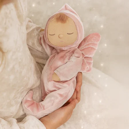 Fairy Aurora dukke fra Olli Ella – blød Dozy Dinkum dukke i rosa velour med fevinger, holdt i armene på et barn.