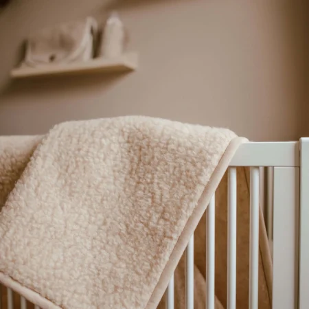 Tæppe til baby i merinould draperet over vugge – blødt, temperaturregulerende babytæppe i 100% merinould